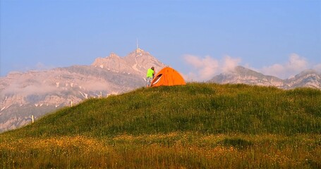 Peaceful Sunrise Setting Featuring Single Adventurer On Grassy Slope Beside Mountain Ridge