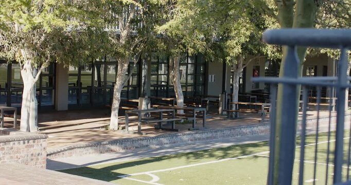 Camera is panning right, revealing picnic tables in school courtyard and empty turf for lunch