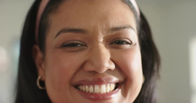 African American woman smiling then laughing after offscreen joke at home, pink headband gold hoops