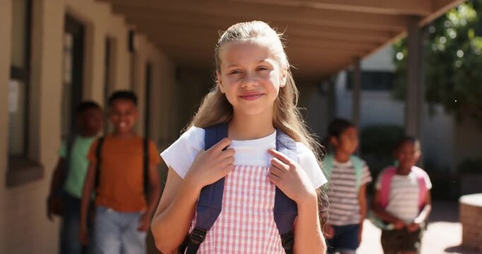Classmates walking corridor between classes, female teen wearing pink gingham holding blue backpack