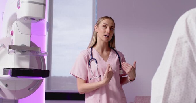 Female nurse in pink scrubs with steth preparing for clinic scan showing position by purple machine