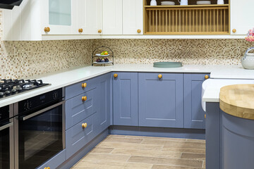 Modern kitchen interior design featuring shaker style blue cabinets, white countertops, mosaic...