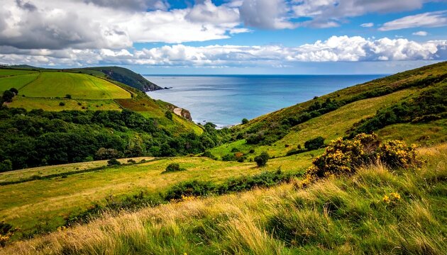 Scenic coastal landscape with rolling green hills, lush vegetation, and a serene ocean view under a cloudy sky.