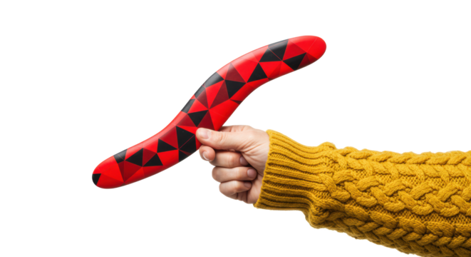 Adult hand in a yellow sweater holding a modern boomerang with a red and black geometric pattern on a transparent background. Concept of modern sport and design - Powered by Adobe