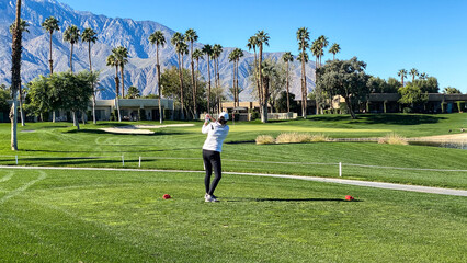 Obraz premium Woman Golfer Teeing Off on Palm Springs Golf Course