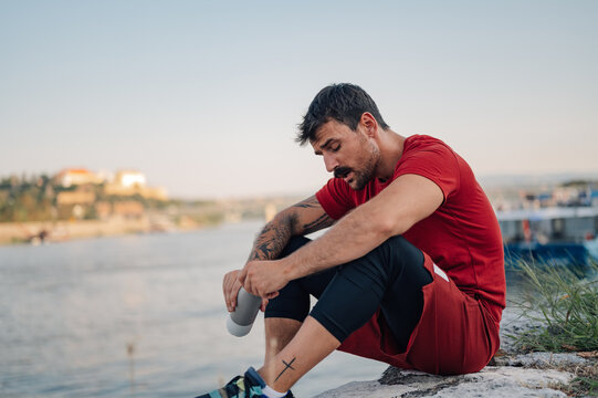 Tired male athlete resting after intense workout by river