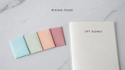 Colorful pastel notes and a blank notebook on a marble surface with a gentle lift reminder for creative inspiration and organization