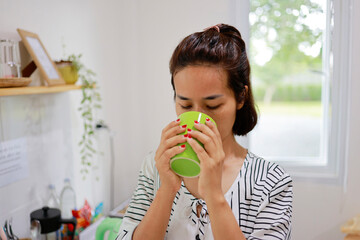 Woman boils water to make coffee to drink in the morning.