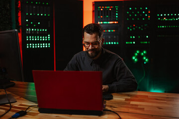 Programmer coding on laptop in server room