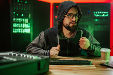 Hooded man hacking in dark server room