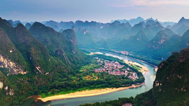 Aerial shot of spectacular karst mountain peaks and winding river with village scenery in Guilin, China. 