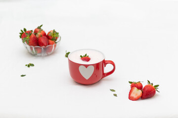 Minimalist still life of a red cup with heart design filled with creamy strawberry foam, topped with fresh fruit and surrounded by ripe strawberries on a clean white background.