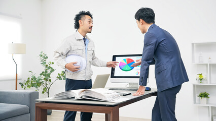 Obraz premium PCを見ながら会議するビジネスパーソンと作業員のグループ