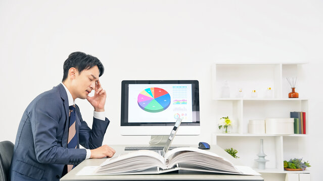 オフィスで仕事をしながら悩む男性ビジネスパーソン