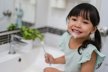 girl child brushing teeth in bathroom