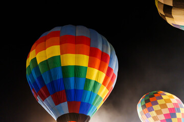 colorful hot air balloons glowing against dark night sky