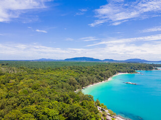 Aerial view of Membalong Beach in Belitung, Indonesia. A pristine tropical coastline featuring turquoise water, lush green forest, and giant granite rock formations.