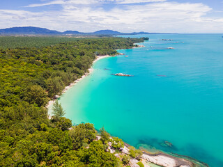 Obraz premium Aerial view of Membalong Beach in Belitung, Indonesia. A pristine tropical coastline featuring turquoise water, lush green forest, and giant granite rock formations.