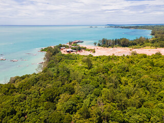 Fototapeta premium Aerial view of Membalong Beach in Belitung, Indonesia. A pristine tropical coastline featuring turquoise water, lush green forest, and giant granite rock formations.