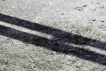 Photo of Shadows on the ground, forming a distinct silhouette. Minimalist composition, light, and contrast in a simple visual. Photo. close up. grey, gray, cement. dark, black. Reflection, reflected. 