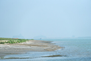 Calm river shore with distant hazy landscape under a serene atmosphere