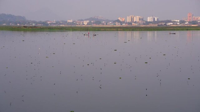 Deepor Beel a freshwater lake in Guwahati Assam with birds flying around two fisherman in a country boat with the city in the backdrop 1