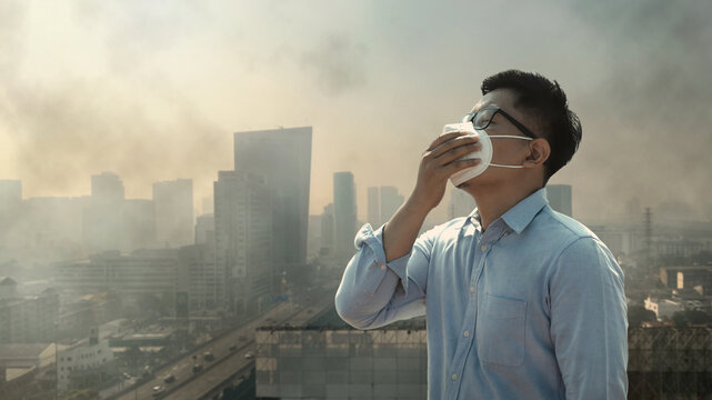 PM2.5 air pollution health impact concept showing a man wearing mask in a smoggy city. Symbol of toxic air, respiratory risk, public health concern, and clean air law protecting people from pollution.