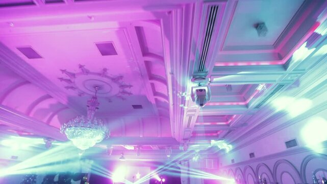 Camera Enters a Grand Banquet Hall with Stage, Spotlight Beams and Crowd Preparing for a Live Performance