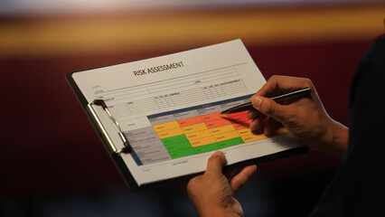 Detailed closeup hand holds clipboard analyzing operational risk assessment matrix chart to ensure...