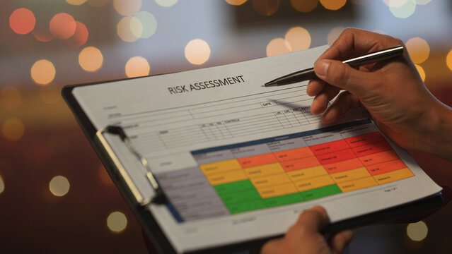 Serious manager checking operational report with caution planning safety strategy risk assessment clipboard with matrix chart.