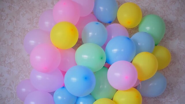 An arrangement of many colored, inflated spherical forms floating together against a patterned backdrop