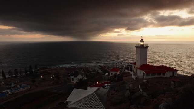 Silver monochrome ocean scene: Lighthouse on bluff over cloudy ocean