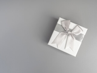 Elegant white gift box with silver ribbon bow on gray background, perfect for marketing promotions, appreciation gift, special occasions, loyalty rewards, celebration, or luxury product packaging.