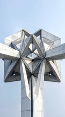 Modern geometric structure with intersecting arms against a pale blue sky