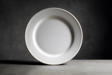 Empty white plate on a grey surface in a dimly lit room showing simple design and texture