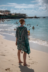 A woman taking in the views of the waves and soft sand at Maho Beach in St. Maarten, a famous destination for sunbathing, swimming, and plane spotting.
