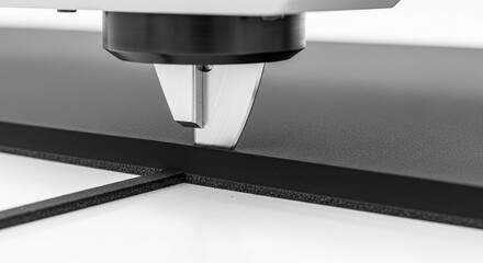 Closeup of a cutting machine precisely scoring a black material, highlighting automation and precision in manufacturing