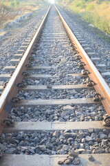 Naklejka premium Railway tracks at morning light, creating strong leading lines and a sense of direction and journey. This image is ideal for themes related to logistics, infrastructure, commuting, adventure