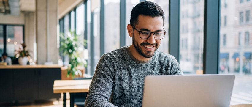 Happy hispanic man working on laptop at home 