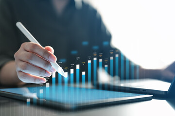 Business analyst using digital tablet and stylus to analyze financial data and growth charts, representing corporate analytics, fintech strategy, investment performance, and data-driven.