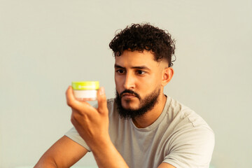 Fototapeta premium Hispanic man examining skin care product for grooming