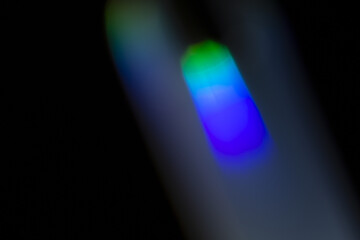 Vertical prism overlay with soft blue and green spectrum glow on dark background, dreamy abstract refraction streak for futuristic minimal design

