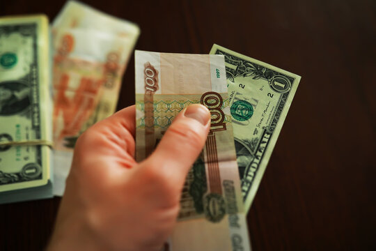 Close-Up of a Hand Holding Mixed Currency Notes Indoors on a Wooden Table