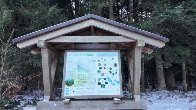 Info board at entrance: Codrii Seculari Slătioara virgin forest map and info in snowy winter woods, Romania