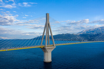 The Rion-Antirion Bridge near Patras in western Greece rises above deep blue water, with striking suspension cables and distant mountains under a vibrant sky. The structure's geometric lines stand out © Florent