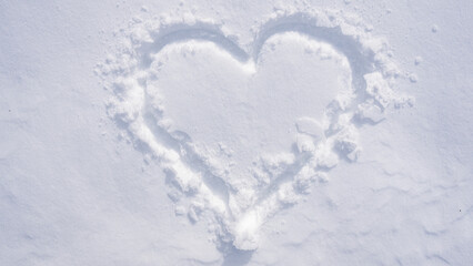 Snow heart on a white winter background. Frosty heart shape in snowy field. Romantic snow heart drawing outdoors. Winter love symbol on frozen surface. Snowflake heart detail. Snow love.