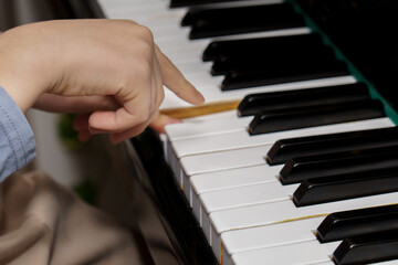 Obraz premium Child's hand pressing piano key. Demonstrating music education, learning instrument, and developing musical skill and talent