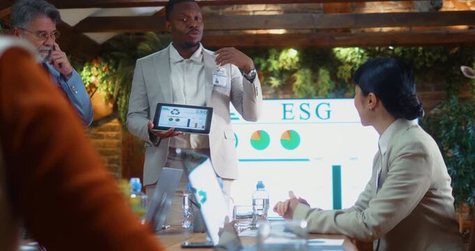 Japanese businesswoman and Black businessman continue discussion during ESG meeting, exchanging ideas and reaching conclusions together, highlighting collaboration and decision making in eco office.