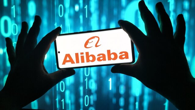 Hands holding smartphone displaying alibaba logo with binary code