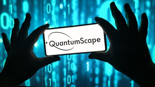 Hands holding smartphone displaying quantumscape logo with binary code